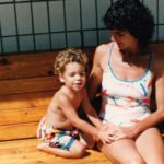 little boy in shorts on a patio with his mother in her swimsuit