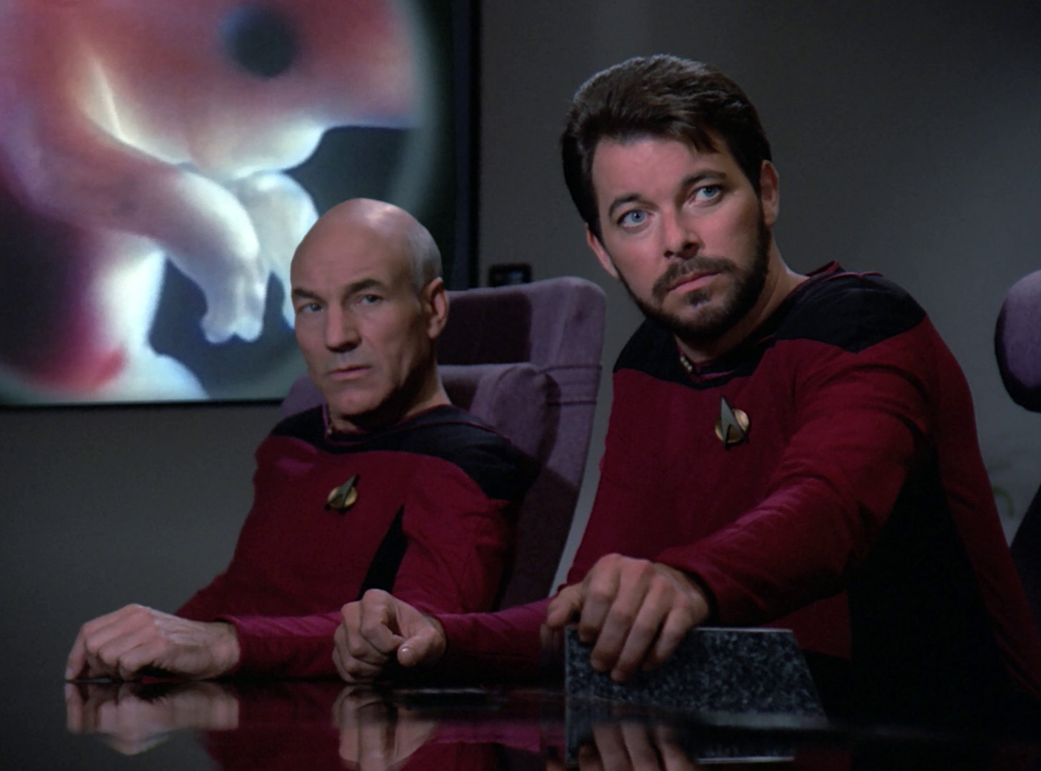 Riker and Picard in the conference room in front of the viewscreen showing Troi's fetus