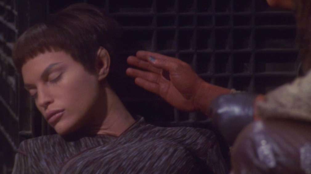T'Pol pretending to be unconscious again as a Ferengi hand reaches to caress her face, from "Acquisition"