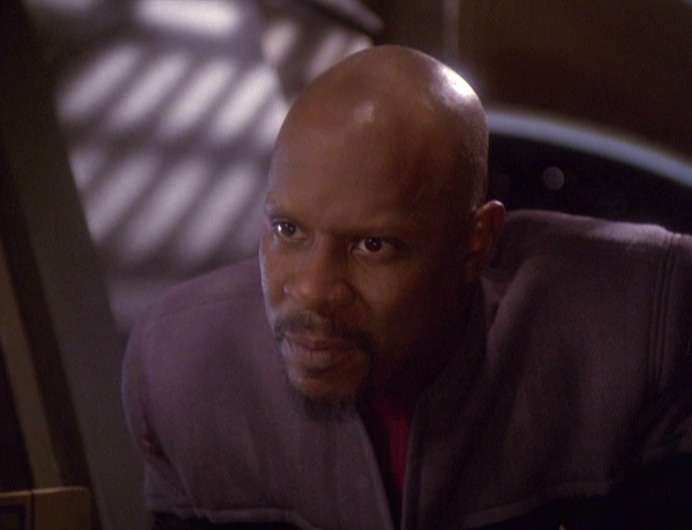 Sisko leaning in to tell Kasidy why he doesn't want to come to Vic's